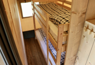 Binnenzicht van een safaritent op Camping de Heerlijkheid Vorenseinde met houten stapelbedden.
