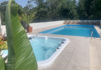 Piscina exterior y jacuzzi rodeados de plantas cerca de una tienda safari en Glamping de Cerveira, Portugal.