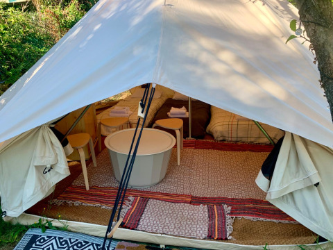 Interior de tienda safari glamping con alfombras, mesas y camas en Glamping de Cerveira, Portugal.