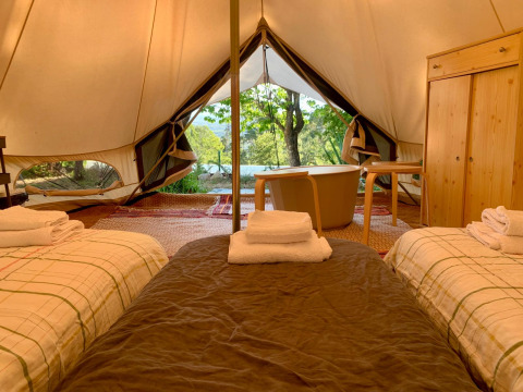 Interior de la tienda Oliveira Bell Standard en Glamping de Cerveira, Portugal, con camas y bañera visible.