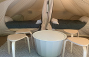 Indretningen af et Camelia XL Bell telt ved Glamping de Cerveira i Portugal, med to senge og moderne møbler.