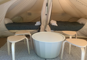 Interieur van de Camelia XL Bell Tent bij Glamping de Cerveira in Portugal, met twee bedden en modern meubilair.