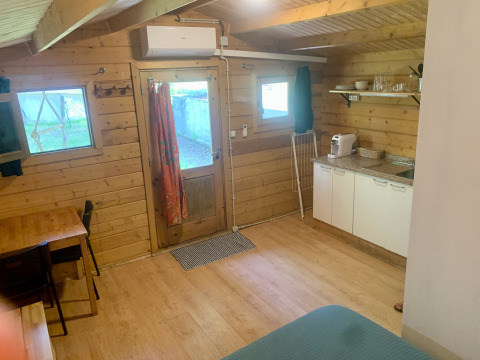 Vista interior de la Azalea Cabin en Glamping de Cerveira, Portugal, con paredes de madera y cocina pequeña.