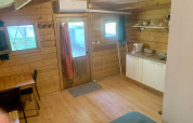 Vista interna della Azalea Cabin al Glamping de Cerveira in Portogallo, con pareti in legno e angolo cottura.