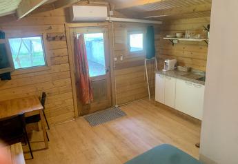 Vista interna della Azalea Cabin al Glamping de Cerveira in Portogallo, con pareti in legno e angolo cottura.