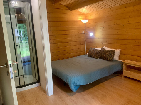 Vista interior de la Azalea Cabin en Glamping de Cerveira, Portugal, con paredes de madera y cama doble.
