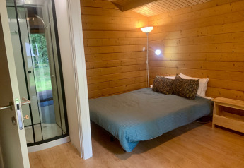 Vista interna della Azalea Cabin al Glamping de Cerveira in Portogallo con pareti in legno e letto doppio.