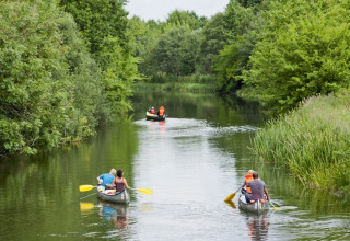 Menschen paddeln in Kanus auf einem Fluss bei Vestbirk Camping im Grünen in der Hauptstadtregion Dänemarks.