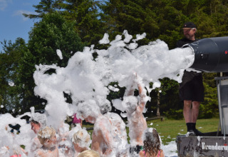 Enfants s'amusant sous la mousse d'un canon à mousse au camping Vestbirk, région capitale du Danemark.