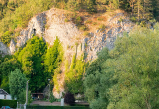 Flod, klipper og træer ved feriepark med glamping. Sommertid og fredelig atmosfære i naturen.