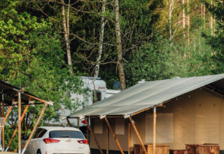 Bungalow e auto al parco vacanze Camp Kyllburg, circondati da foresta in Renania-Palatinato, Germania.