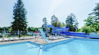 Piscina exterior con tumbonas y un gran tobogán azul en Vestbirk Camping, Dinamarca.