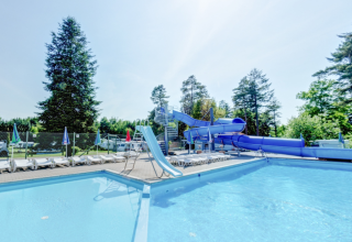 Piscina exterior con tumbonas y un gran tobogán azul en Vestbirk Camping, Dinamarca.