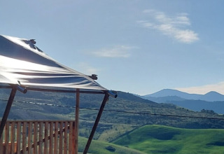 Vue ensoleillée depuis Vestbirk Camping, tente moderne, collines vertes et ciel bleu au Danemark.
