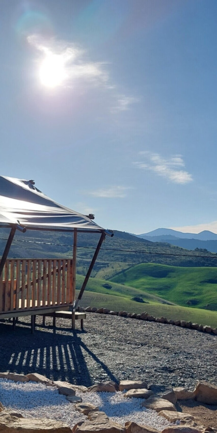 Vista soleggiata da Vestbirk Camping con tenda, colline verdi e cielo limpido in Danimarca.