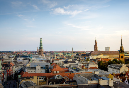 Vista panorámica del centro de Copenhague con torres históricas y tejados tradicionales bajo un cielo azul.