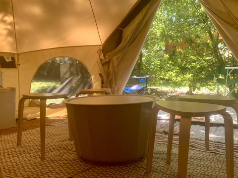 Interieur van het Laurelia XL Family Tent bij Glamping de Cerveira, met tafels, stoelen en veel groen uitzicht.
