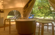 Binnenkant van de Laurelia XL Family Tent bij Glamping de Cerveira met tafels, stoelen en groene omgeving.
