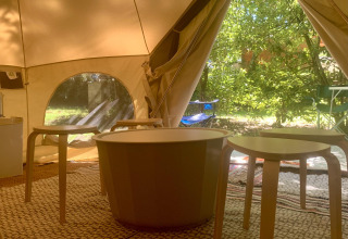 Interieur van het Laurelia XL Family Tent bij Glamping de Cerveira, met tafels, stoelen en veel groen uitzicht.