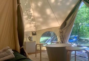 Vista interior de la carpa Laurelia XL Family Tent en Glamping de Cerveira, Portugal, con muebles y naturaleza.