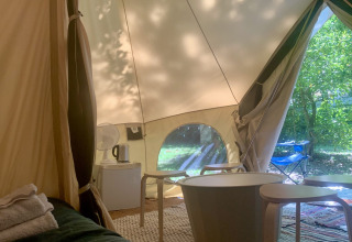 Interieur van de Laurelia XL Family Tent bij Glamping de Cerveira in Portugal, met meubels en zicht op tuin.