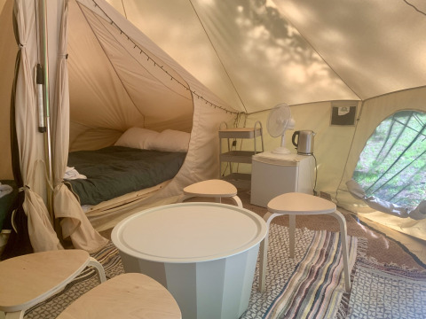 Interior de la tienda Laurelia XL Family con cama, mesa y taburetes en Glamping de Cerveira, Portugal.