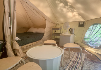 Interior de la tienda Laurelia XL Family con cama, mesa y taburetes en Glamping de Cerveira, Portugal.