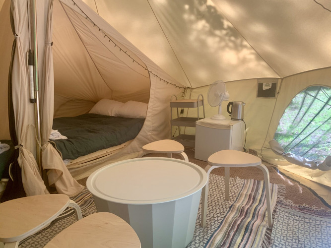 Binnenkant van Laurelia XL Family safaritent met bed, tafels en stoelen bij Glamping de Cerveira, Portugal.