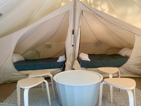 Interieur van een ruime safaritent met twee bedden en tafels bij Glamping de Cerveira in Portugal.
