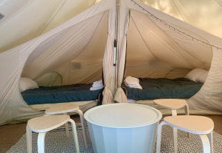Interieur van een ruime safaritent met twee bedden en tafels bij Glamping de Cerveira in Portugal.