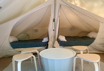 Indretning af en rummelig familietelt med to senge og borde hos Glamping de Cerveira i Portugal.