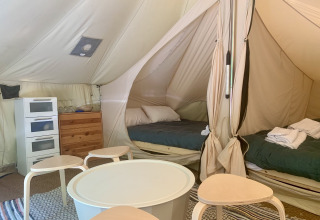 Indvendigt billede af Laurelia XL Family Tent hos Glamping de Cerveira i Portugal med senge og møbler.
