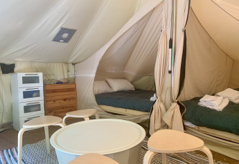 Vista interior de la tienda Laurelia XL Family Tent en Glamping de Cerveira, Portugal, con camas y muebles.