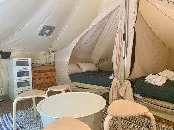 Vista interior de la tienda Laurelia XL Family Tent en Glamping de Cerveira, Portugal, con camas y muebles.