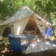 Safari telt Laurelia XL Family Tent med åbent indgangsparti, udendørs stole og bord under skyggefulde træer.