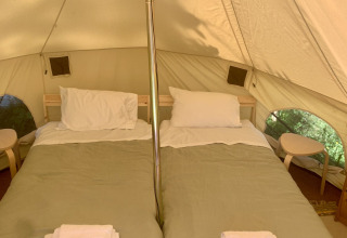 Binnenkant van een safaritent met twee bedden en witte lakens bij Glamping de Cerveira in Portugal.