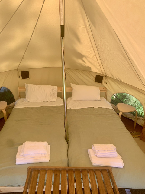 Binnenkant van een safaritent met twee bedden en witte lakens bij Glamping de Cerveira in Portugal.