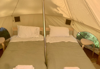 Interno di una tenda safari con due letti e lenzuola bianche a Glamping de Cerveira, Portogallo.