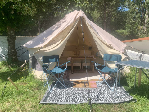Carvalho 4 Meter XL Bell Tent op Glamping de Cerveira in Portugal, met stoelen en tafel buiten de tent.