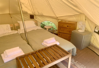 Indretning i Carvalho 4 Meter XL Bell Tent med to senge, kommode, ventilator og mini køleskab på Glamping de Cerveira.