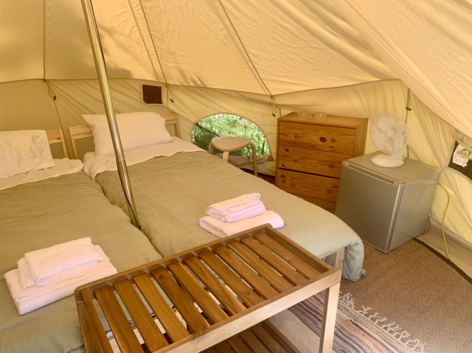 Binnenkant van de Carvalho 4 Meter XL Bell Tent met twee bedden, kast en koelkast bij Glamping de Cerveira.