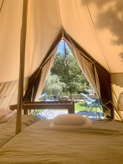 Zicht vanuit een safari tent met bedden en tuinmeubilair bij Glamping de Cerveira in Portugal.