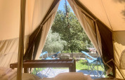 Udsigt fra indersiden af en safari telt med senge, håndklæder og terrassemøbler på Glamping de Cerveira i Portugal.