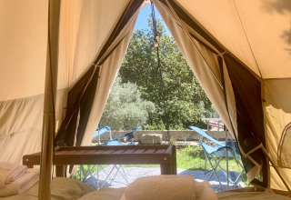 Udsigt fra indersiden af en safari telt med senge, håndklæder og terrassemøbler på Glamping de Cerveira i Portugal.