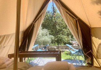 Udsigt fra indersiden af en safari telt med senge, håndklæder og terrassemøbler på Glamping de Cerveira i Portugal.