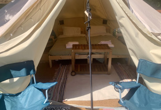 Interieur van de Carvalho 4M XL safaritent met bed en stoelen bij Glamping de Cerveira in Portugal.