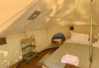 Indretning af Carvalho 4 Meter XL Bell Tent med dobbeltseng og campingmøbler på Glamping de Cerveira i Portugal.