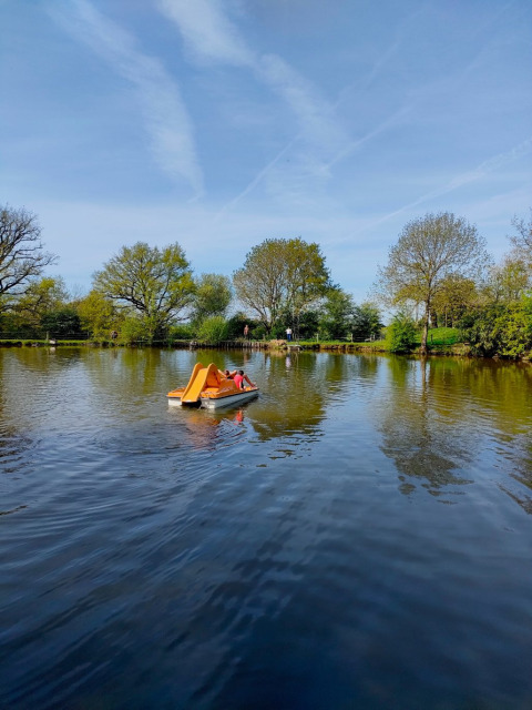 Barca a pedales con tobogán naranja en un lago soleado de Feather Down La Flocellière en Vendée, Pays de la Loire, Francia.