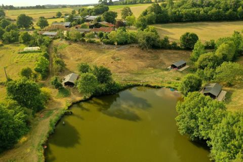 Vista aérea de Feather Down La Flocellière en Vendée con lago, cabañas y campos en Pays de la Loire, Francia.