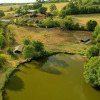 Aerial view of Feather Down La Flocellière en Vendée, showcasing the lake, cabins, and fields in Pays de la Loire.